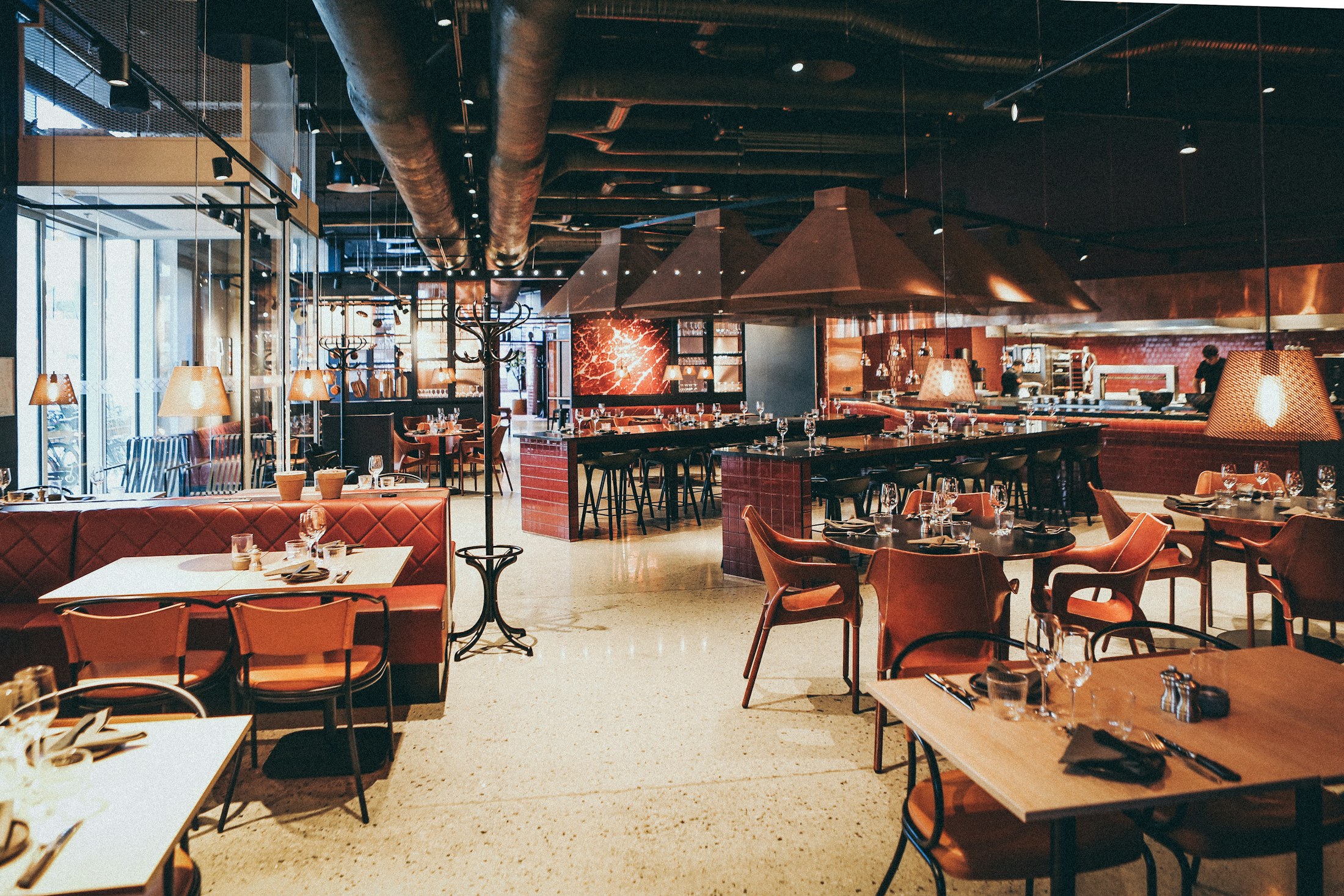 Restaurant dining room with tables, chairs, and an open kitchen