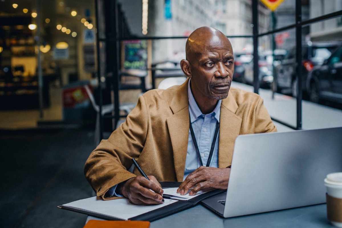 Manager reviewing information on a laptop from a cafe table.