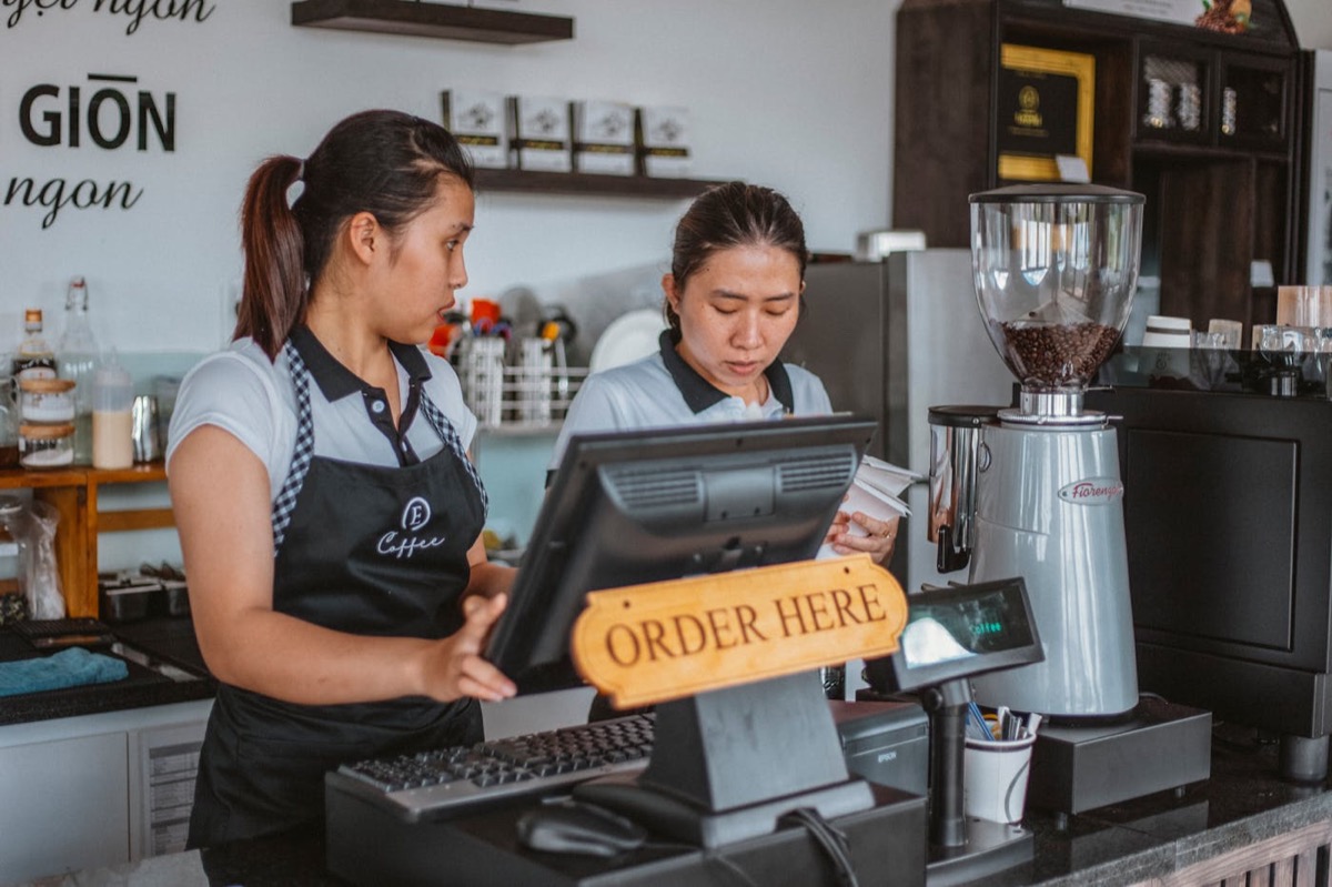Restaurant staff working at a point of sale counter.